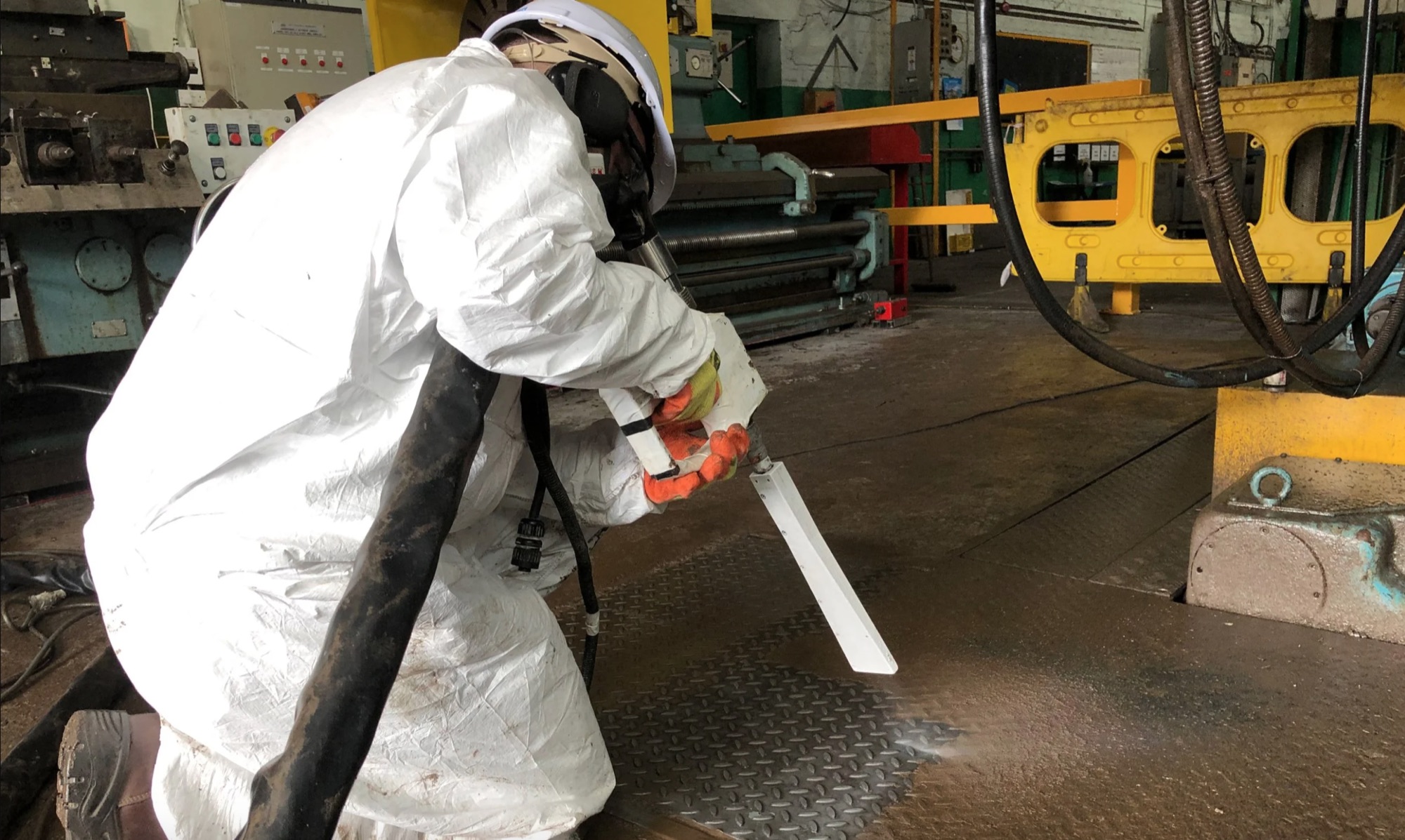 Technician in protective suit dry ice blasting a building interior